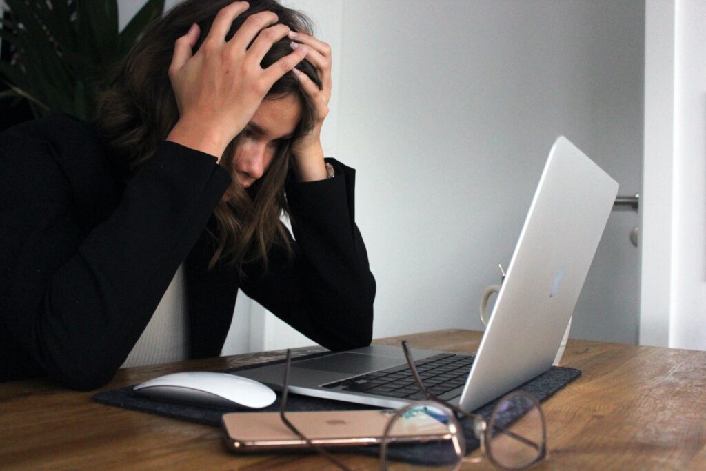Business woman frustrated and overwhelmed at work while sitting at her laptop representing someone struggling with an ADHD diagnosis. Therapy for ADHD in Charlotte, NC can help you manage your symptoms effectively.
