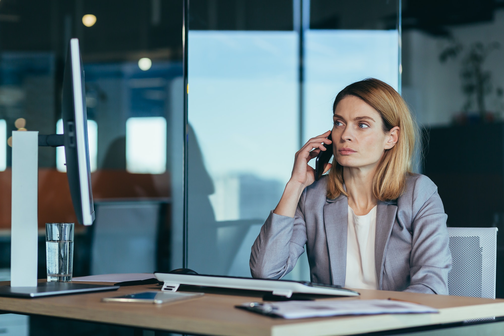 Serious and anxious business woman talking on the phone, working in a modern office